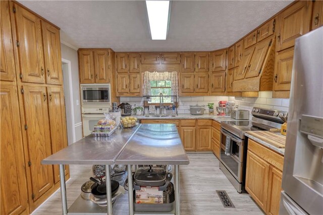 78 N Pomona Rd, Hampton, GA 30228 - kitchen with appliances with stainless steel finishes, a sink, light countertops, light wood-style flooring, and decorative backsplash