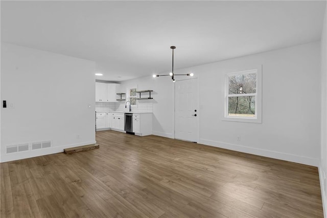 9148 Homewood Dr, Riverdale, GA 30274 - unfurnished living room featuring visible vents, wood finished floors, a sink, baseboards, and a notable chandelier
