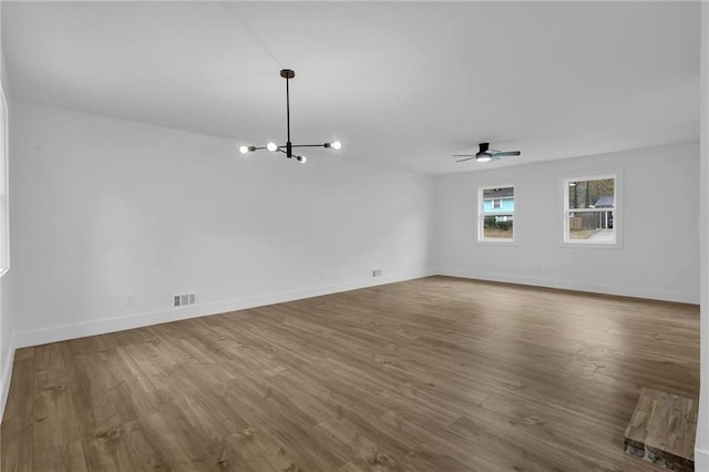 9148 Homewood Dr, Riverdale, GA 30274 - unfurnished living room featuring dark wood-style flooring, ceiling fan with notable chandelier, and baseboards