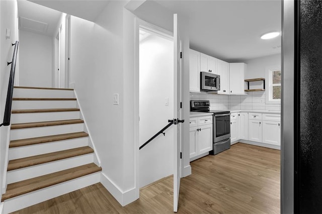9148 Homewood Dr, Riverdale, GA 30274 - kitchen featuring tasteful backsplash, white cabinets, light countertops, appliances with stainless steel finishes, and light wood-style floors