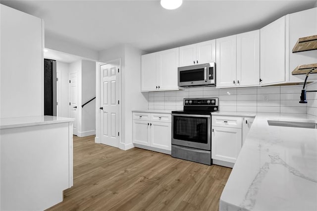 9148 Homewood Dr, Riverdale, GA 30274 - kitchen featuring light wood-type flooring, a sink, backsplash, and appliances with stainless steel finishes