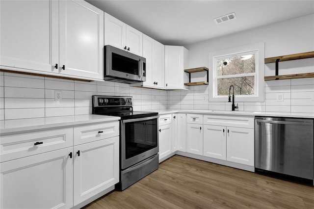 9148 Homewood Dr, Riverdale, GA 30274 - kitchen with visible vents, open shelves, light countertops, stainless steel appliances, and decorative backsplash
