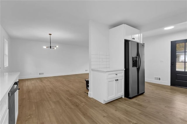 9148 Homewood Dr, Riverdale, GA 30274 - kitchen featuring visible vents, black refrigerator with ice dispenser, light countertops, white cabinetry, and light wood finished floors
