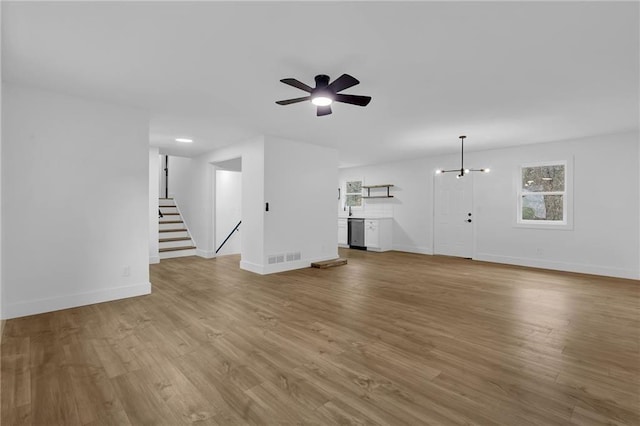 9148 Homewood Dr, Riverdale, GA 30274 - unfurnished living room with baseboards, stairway, visible vents, ceiling fan, and wood finished floors