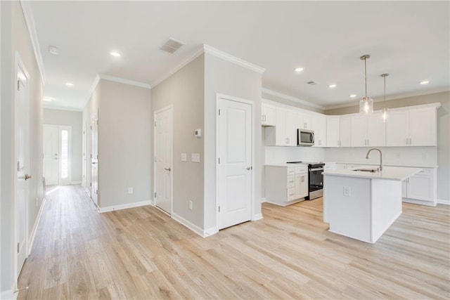 kitchen with white cabinets, hanging light fixtures, and an island with sink