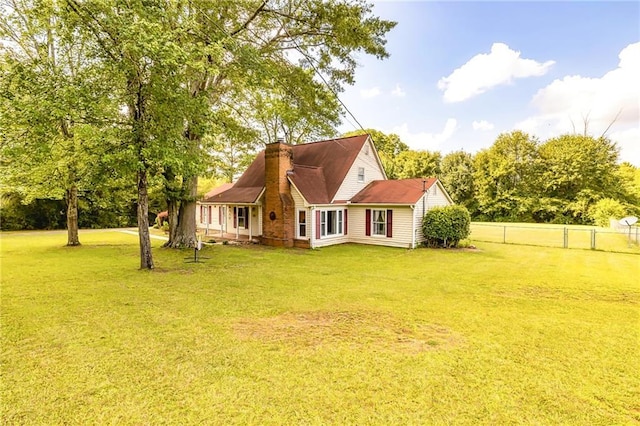 back of house featuring a yard, fence, and a chimney