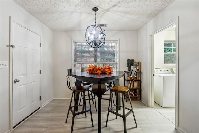 dining space featuring washer / dryer, a textured ceiling, a wealth of natural light, and an inviting chandelier