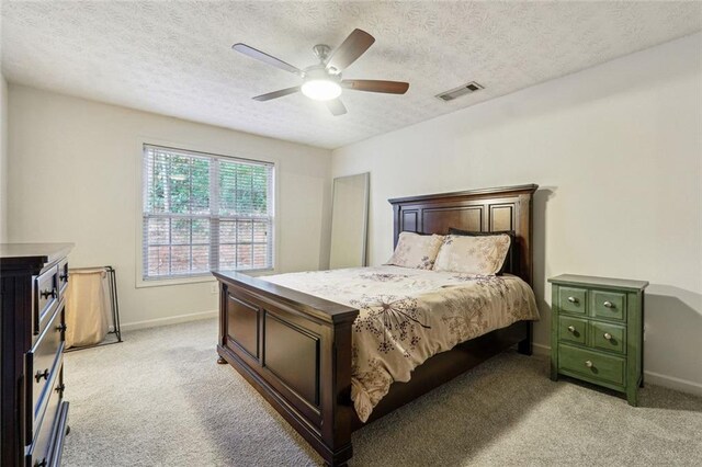 bedroom featuring a textured ceiling, ceiling fan, and light carpet