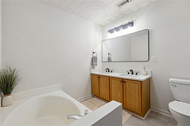 bathroom featuring a bathtub, toilet, a textured ceiling, and vanity