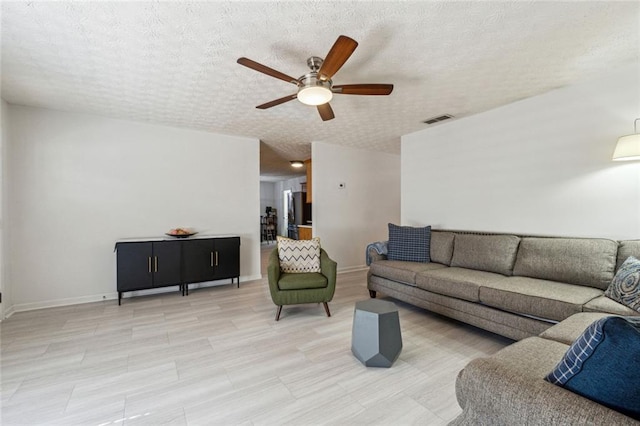 living room featuring ceiling fan and a textured ceiling