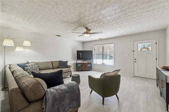 living room featuring a textured ceiling and ceiling fan