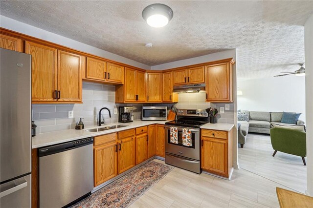 kitchen featuring appliances with stainless steel finishes, tasteful backsplash, a textured ceiling, ceiling fan, and sink