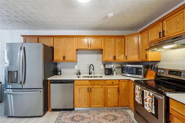 kitchen featuring backsplash, sink, a textured ceiling, and appliances with stainless steel finishes