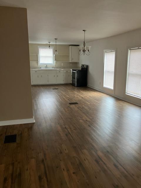 kitchen with white cabinets, decorative light fixtures, stainless steel fridge, and sink