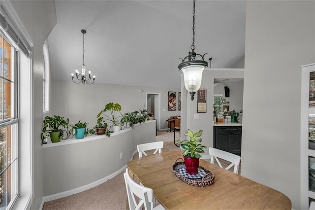 carpeted dining room featuring lofted ceiling and an inviting chandelier