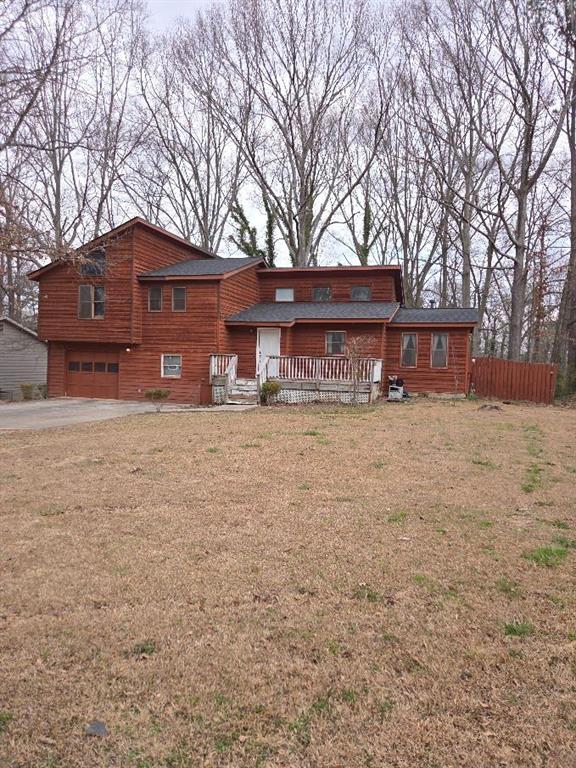 view of front facade with driveway, an attached garage, fence, and a front yard