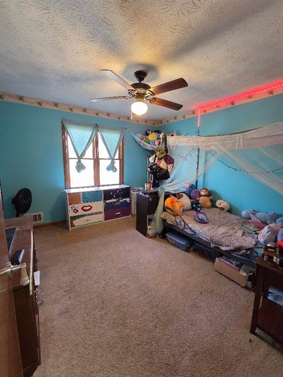 bedroom featuring a textured ceiling, carpet flooring, and a ceiling fan