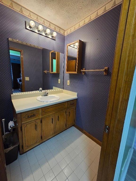 bathroom featuring a textured ceiling, tile patterned floors, vanity, and wallpapered walls