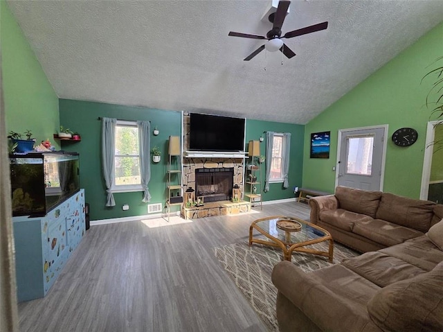 living room with lofted ceiling, ceiling fan, a fireplace, wood finished floors, and baseboards