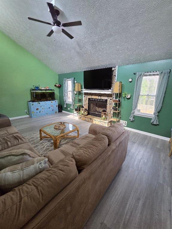 living room featuring lofted ceiling, a healthy amount of sunlight, a fireplace, and wood finished floors