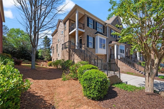 view of side of home featuring stairs, a balcony, and brick siding