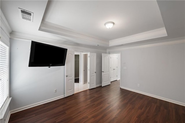 unfurnished bedroom featuring a raised ceiling, ornamental molding, wood finished floors, and baseboards