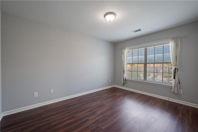 empty room with dark wood-type flooring and baseboards