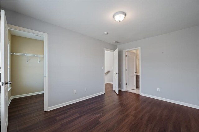 unfurnished bedroom featuring wood finished floors, baseboards, and a closet