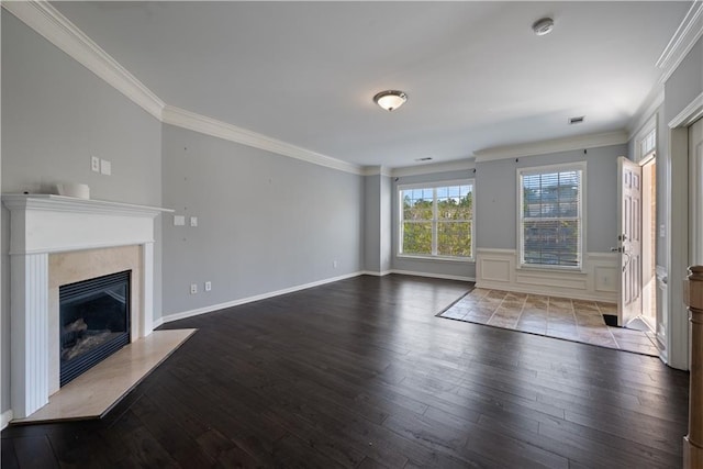 unfurnished living room with wood finished floors, ornamental molding, a fireplace, and wainscoting