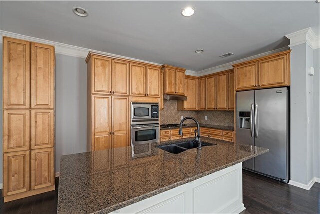 kitchen with stainless steel appliances, a sink, decorative backsplash, dark wood finished floors, and dark stone countertops