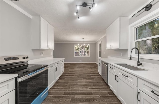 kitchen featuring baseboards, a sink, dark wood finished floors, a textured ceiling, and stainless steel appliances