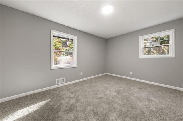 empty room with baseboards, visible vents, and carpet floors