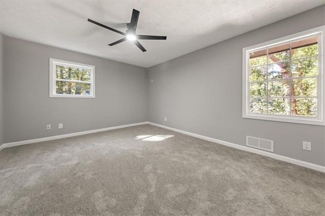 unfurnished room featuring visible vents, baseboards, ceiling fan, carpet, and a textured ceiling