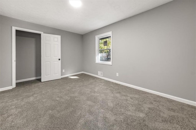 unfurnished bedroom featuring visible vents, baseboards, and dark colored carpet