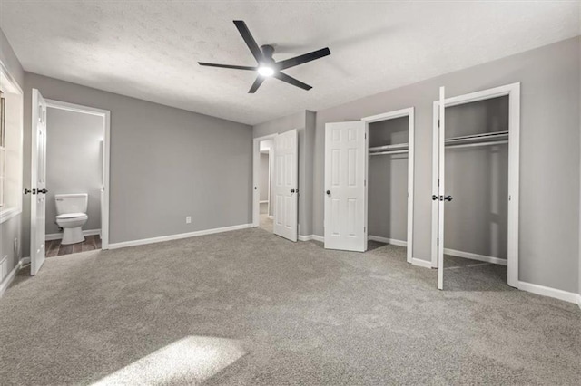 unfurnished bedroom with baseboards, connected bathroom, multiple closets, and carpet floors