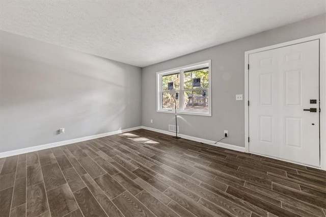 empty room with a textured ceiling, baseboards, dark wood finished floors, and visible vents
