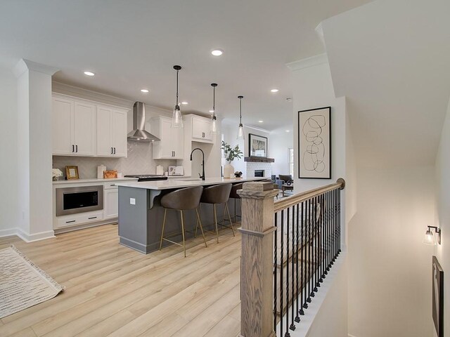 living room featuring light hardwood / wood-style floors, crown molding, ceiling fan, and a fireplace