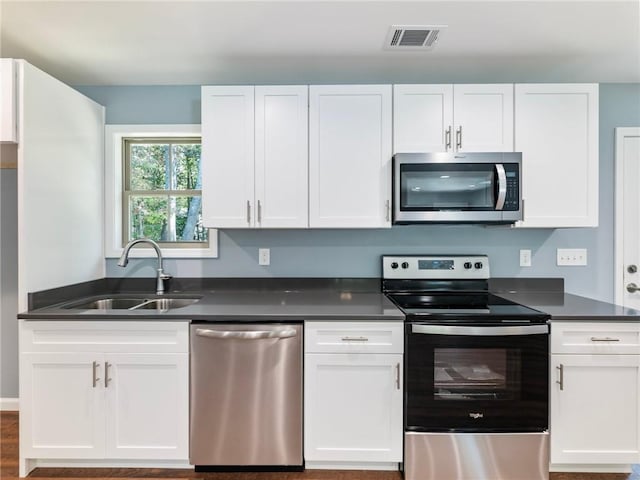 kitchen featuring a sink, visible vents, white cabinetry, appliances with stainless steel finishes, and dark countertops