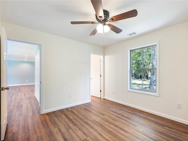 empty room featuring baseboards, visible vents, ceiling fan, and wood finished floors