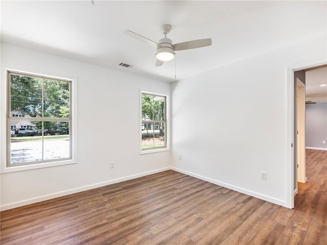 unfurnished room featuring a ceiling fan, baseboards, visible vents, and wood finished floors