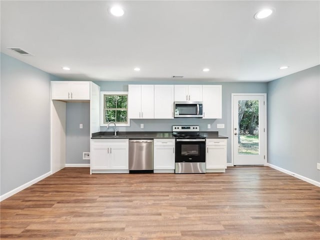 kitchen with a sink, visible vents, white cabinetry, appliances with stainless steel finishes, and dark countertops