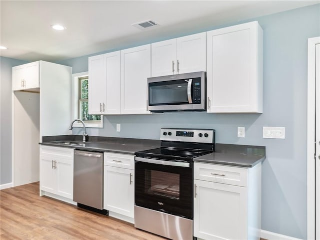 kitchen with stainless steel appliances, a sink, visible vents, and white cabinetry