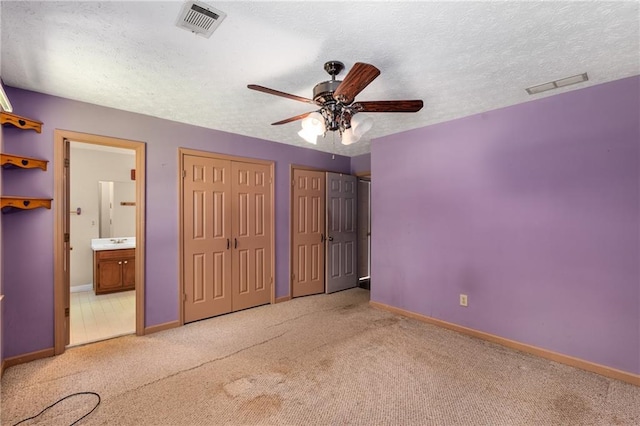 2617 Laurel Woods Ln SE, Conyers, GA 30094 - unfurnished bedroom featuring multiple closets, carpet floors, ensuite bath, and a textured ceiling