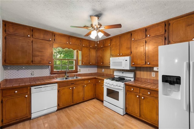 2617 Laurel Woods Ln SE, Conyers, GA 30094 - kitchen with white appliances, brown cabinetry, tile counters, light wood finished floors, and a textured ceiling