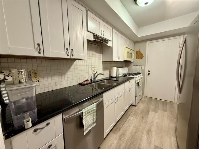 6851 Roswell Rd Unit D33, Atlanta, GA 30328 - kitchen with appliances with stainless steel finishes, a sink, light wood-style floors, white cabinets, and tasteful backsplash