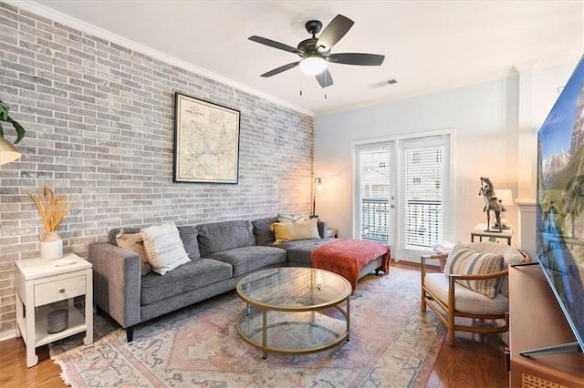 living room with crown molding, brick wall, and wood-type flooring