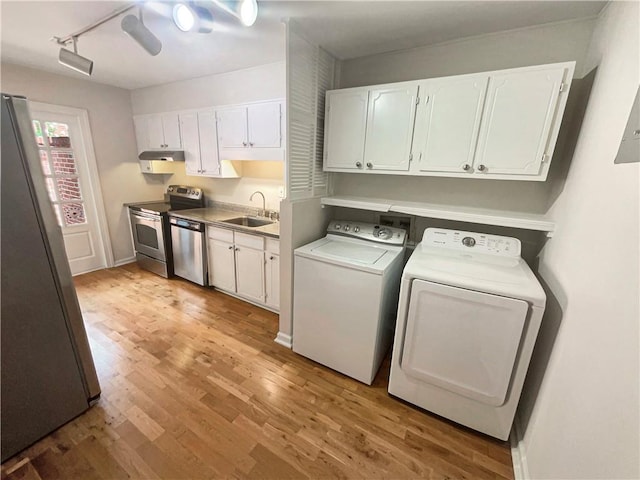 laundry area with light hardwood / wood-style flooring, sink, washer and clothes dryer, and track lighting