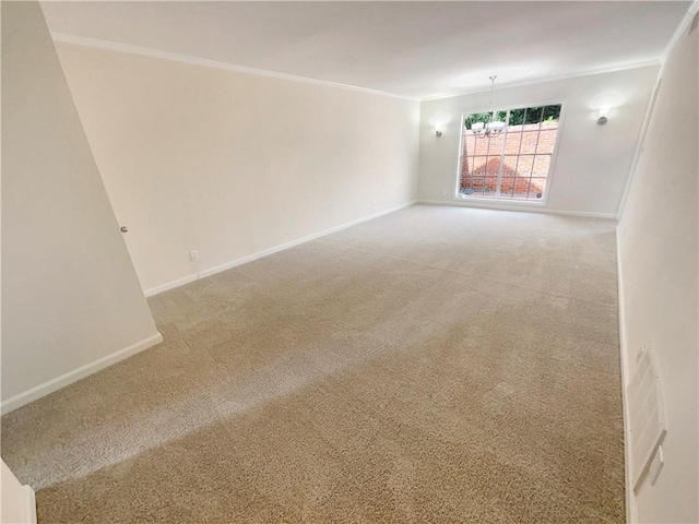 spare room with ornamental molding, carpet floors, and a chandelier