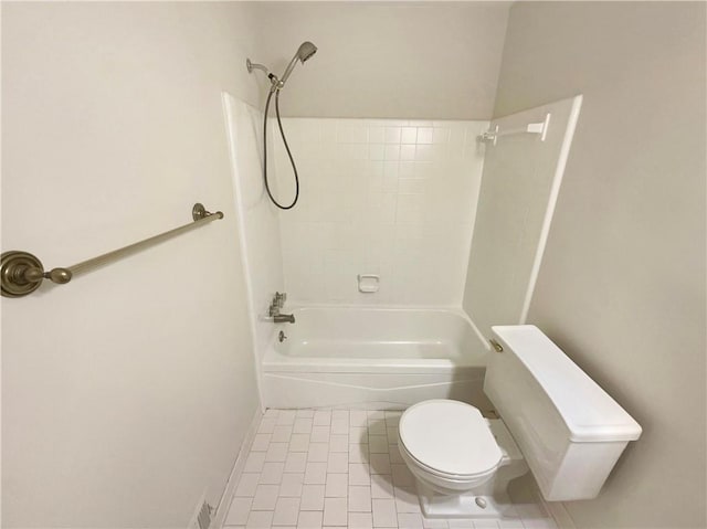 bathroom featuring tile patterned flooring, tiled shower / bath combo, and toilet