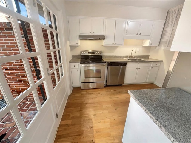 kitchen with stainless steel appliances, sink, white cabinets, and light hardwood / wood-style flooring